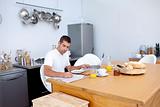 Busy man having breakfast and working in kitchen 