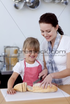 Mother teaching daughter how to cut bread