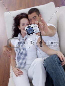Couple playing with a camera in living-room