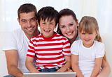 Smiling family at home using a laptop
