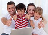 Family at home using a laptop with thumbs up