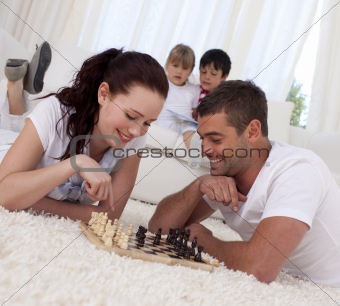 Smiling couple playing chess on floor in living-room