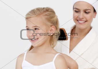 Young mother doing daughter's hair