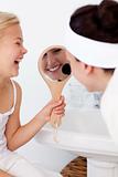Daughter holding a mirror and mother putting makeup