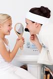 Little girl holding a mirror and mother putting makeup