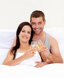 Couple tusting with champagne in bed