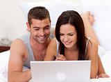 Couple in bed using a laptop