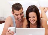 Couple in bed having fun with a laptop