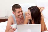 Husband and wife in bed using a laptop