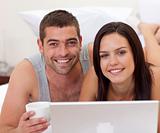 Portrait of couple in bed using a laptop