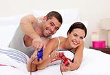 Husband and wife playing videogames in bed