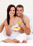Couple eating fruit and orange juice in bed