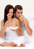 Couple eating fruit and drinking orange juice in bed