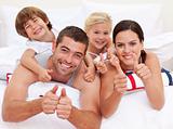 Family playing in bed with thumbs up