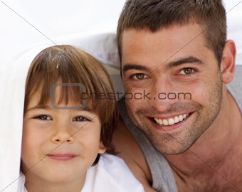 Portrait of dad and son under the bedsheets