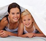 Mother and daughter under the bedsheets