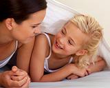 Mother and daughter talking under the bedsheets