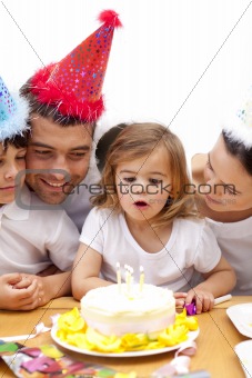 Girl blowing out candles in her birthday's day with family