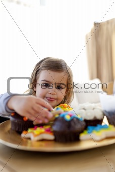 Hungry little girl looking at confectionery at home
