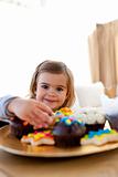 Smiling little girl eating confectionery at home