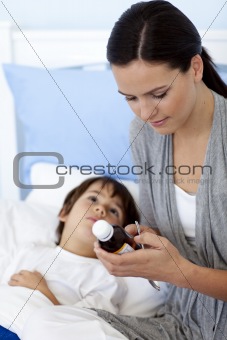 Mother giving her son syrup