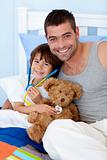 Happy father and son playing doctors in bed with a teddy bear