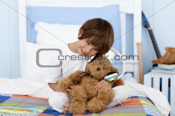 Little boy playing with headphones and teddy bear