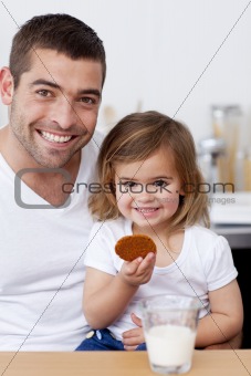 Father and daughter eating biscuits with milk