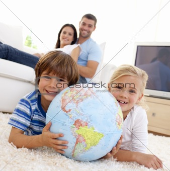 Children playing with a terrestrial globe at home