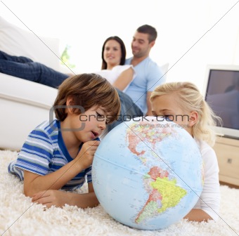 Children playing with a terrestrial globe in living-room