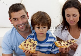 Prents and boy eating pizza in living-room
