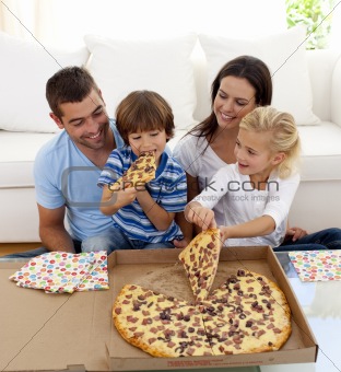 Young family eating pizza in living-room