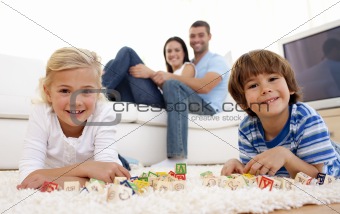 Children painting on floor with their family in sofa