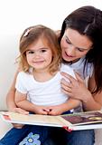 Little girl reading a book withher mother