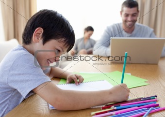 Boy drawing and parents working at home