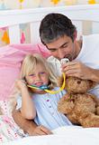 Daughter and father playing doctors with a teddy bear