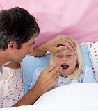 Father taking his daughter's temperature with a thermometer