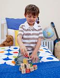 Little boy playing with alphabet cubes in his bedroom