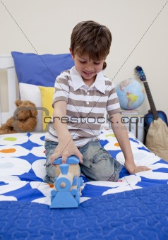 Happy boy playing with a train in his bedroom