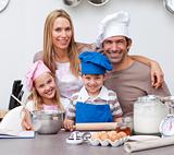 Smiling parents helping children baking in the kitchen