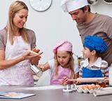 Mother and father helping children baking in the kitchen