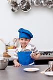 Little boy with blue hat and apron baking