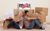 Happy couple sitting on floor after buying house