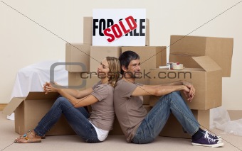 Happy couple sitting on floor after buying house