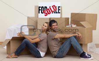 Wife and husband relaxing on floor unpacking boxes