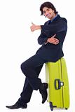 Corporate man sitting above the luggage showing thumbsup