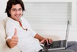 young man using laptop showing thumbs up