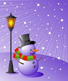 Snowman stands under a lamp on a snowy evening