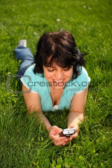 Woman lying on the lawn using mobile
