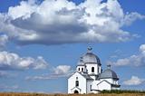 White orthodox church against the blue sky with clouds.